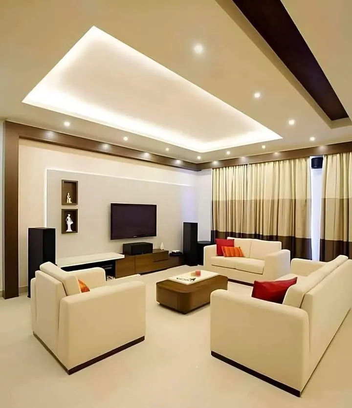 Living room with a recessed ceiling, cove lighting and a TV wall with display niches