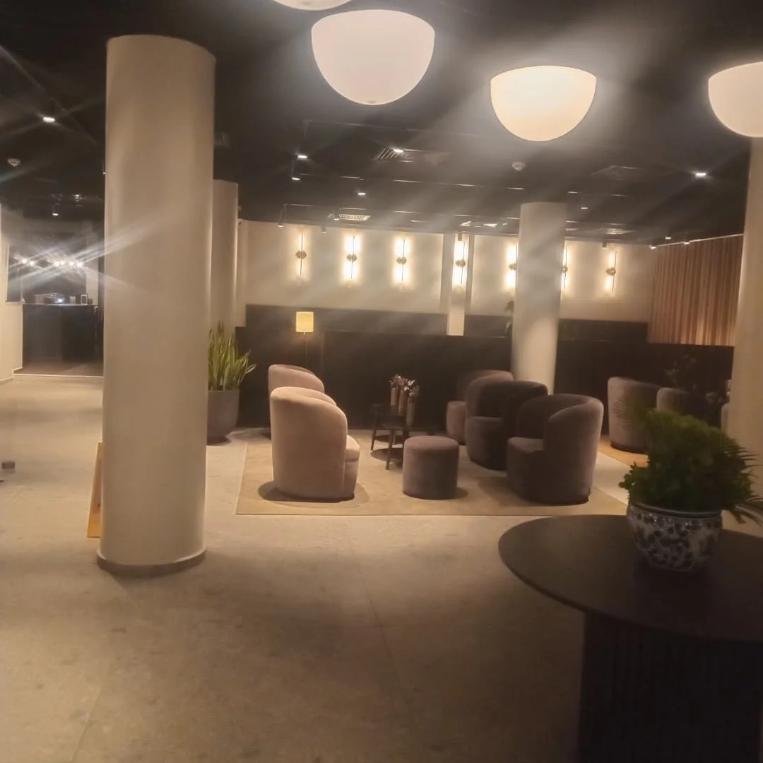 Hotel lobby seating area with round columns, armchairs and a row of wall lights