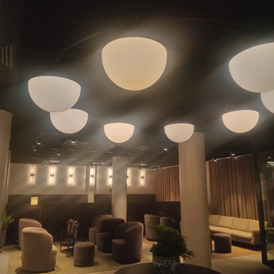 Cluster of white half-dome pendant lights over a hotel lounge with armchairs and wall lights