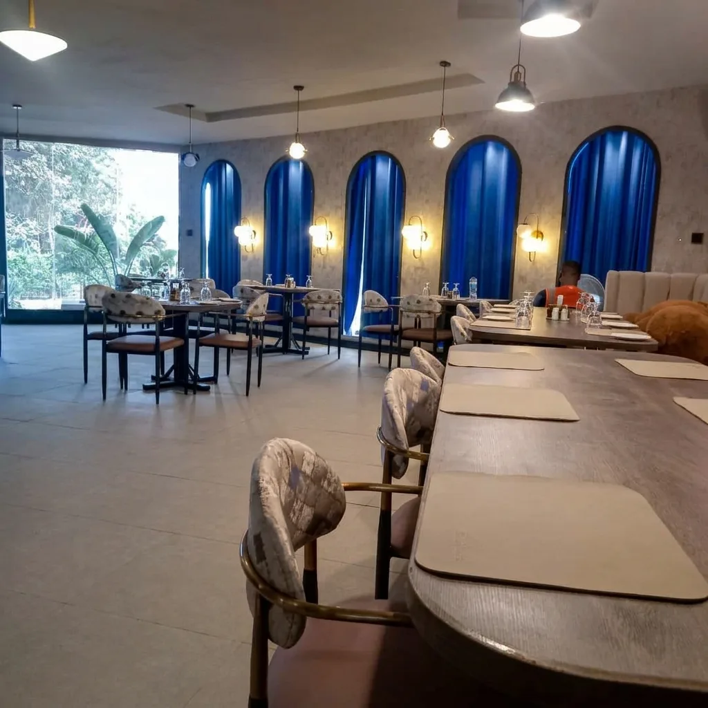 AI-generated image: dining hall with tall arched windows hung with blue curtains, wall lights and long tables
